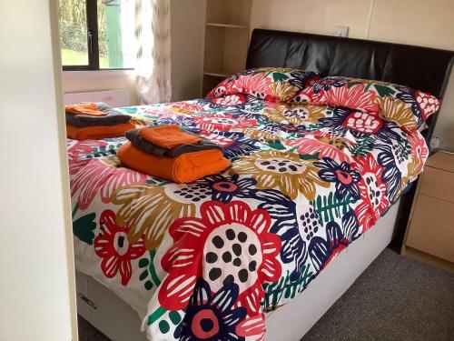a bed with a colorful comforter on it at tranquil holiday home Devon Cornwall border Bude in Pyworthy