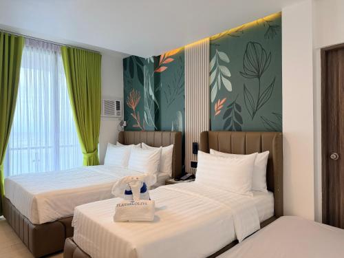 two beds in a hotel room with green walls at PlayaLolita Beach Resort in Calatagan