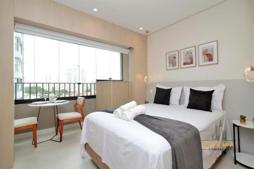 a bedroom with two beds and a table and a balcony at Raízes Studios Tatuapé – Mitre 4 in São Paulo