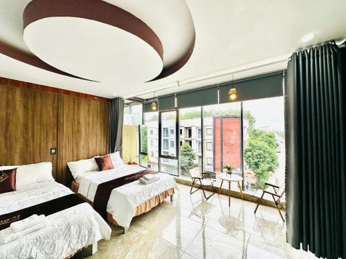 a bedroom with two beds and a large window at Sunny 1 Hometel Vinh Long in Vĩnh Long