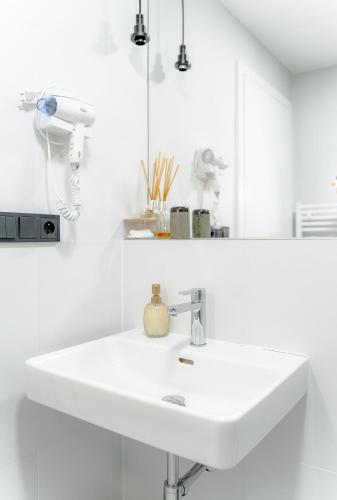 a white bathroom with a sink and a mirror at Jasminn Apartments in Prague