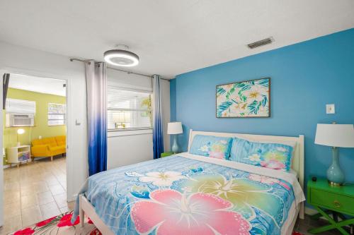 a bedroom with blue walls and a bed with flowers on it at Walk to the Beach and Village - Hibiscus Villa in Siesta Key