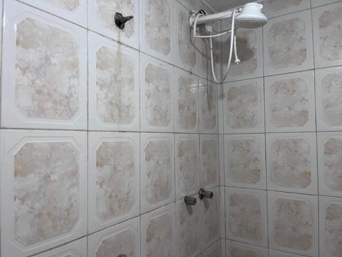 a bathroom with white tile walls and a shower at Pousada Fronteira City in Foz do Iguaçu