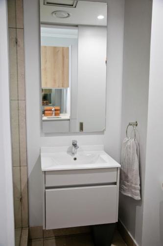 a white bathroom with a sink and a mirror at Ad Astra Studio Apartment - Waterfall in Midrand