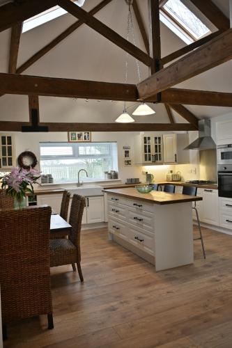 a kitchen with white cabinets and a table with chairs at Stunning Barn Conversion next to Horse Field sleeps 10 in Morpeth