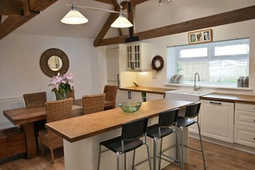 a kitchen with white cabinets and a wooden island with bar stools at Stunning Barn Conversion next to Horse Field sleeps 10 in Morpeth