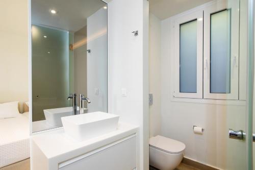 a white bathroom with a sink and a toilet at Glyfada Glow Suites by CorfuEscapes in Glyfada