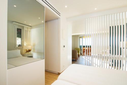 a white bedroom with a bed and a living room at Glyfada Glow Suites by CorfuEscapes in Glyfada