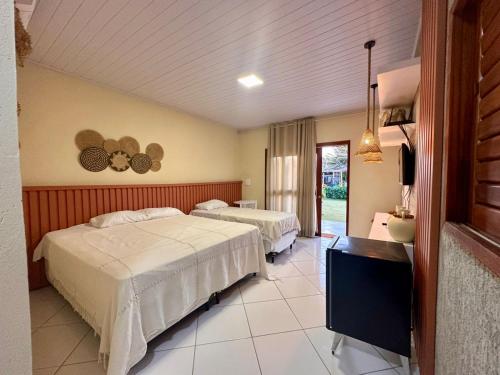 a hotel room with two beds and a television at Juscelino Pousada lazer in Tibau