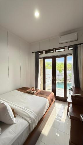 a bedroom with a large bed and a large window at Amerthya Villa in Banjar