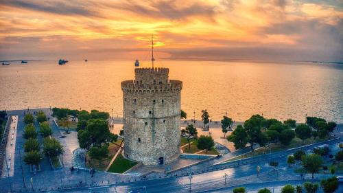 a castle in the middle of the water with a sunset at Le Grace, Urban Retreat near Near CityCenter & Sea in Thessaloniki