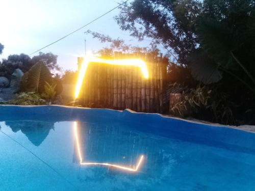 a swimming pool with the sun reflecting in the water at Ancient Gardens Villa in Pinnawala