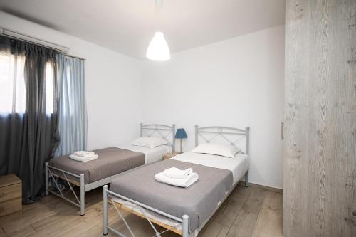 two beds in a room with white walls at The Eagle Merchia Mykonos in Merchia Beach