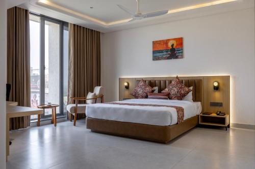 a hotel room with a bed and a large window at Hotel Neptune Mansingh Inn in Morbi