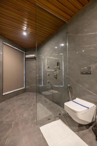 a bathroom with a toilet and a glass shower at Hotel Neptune Mansingh Inn in Morbi