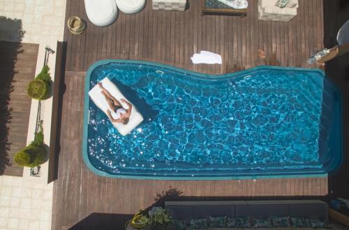 an overhead view of a woman laying in a swimming pool at Marilyn Manor, Exclusive Hideway, By ThinkVilla in Gouves