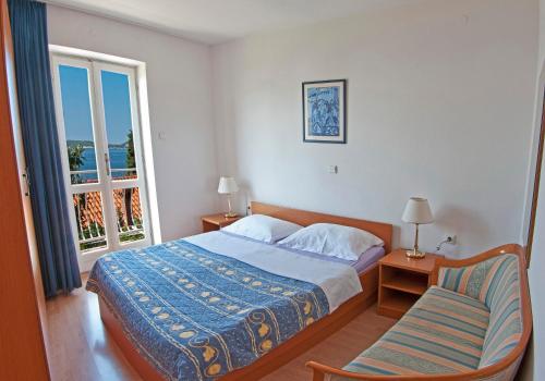 a bedroom with a bed and a chair and a window at Holiday Home Ivanino in Dubrovnik