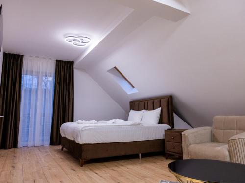 a bedroom with a bed and a couch and a chair at Nubia Central Apartments in Bistriţa