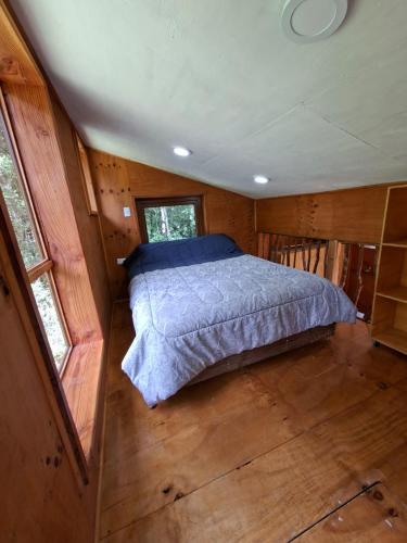a bedroom with a bed in a wooden house at Refugio Purrunko in Pucón