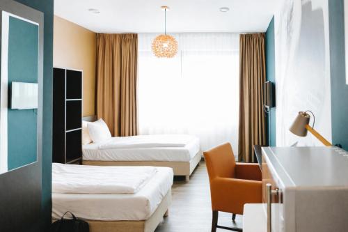 a hotel room with two beds and a chair at The Hague Teleport Hotel - Free Parking in The Hague