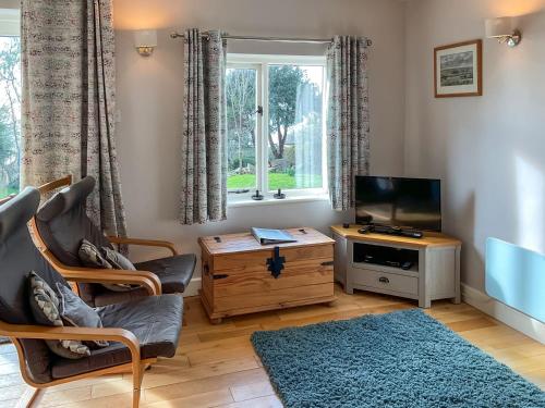 a living room with a television and a chair and a table at Whispering Pines - Uk51248 in Swyre