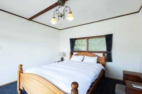 a bedroom with a bed with white sheets and a window at 太宰府らたん - Dazaifu Ratan in Dazaifu