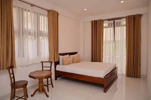 a bedroom with a bed and a chair and windows at Windsor Crest in Kandy