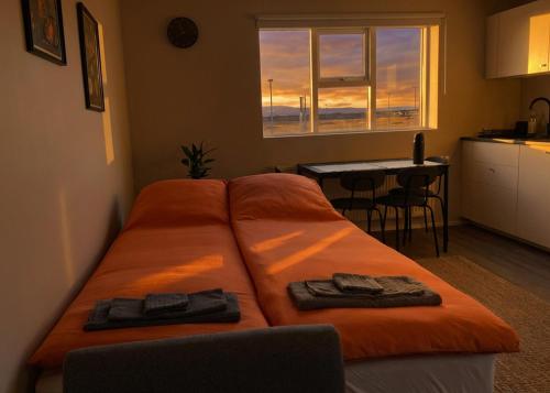 a bedroom with an orange bed with towels on it at Faxaflatir Apartments in Hella