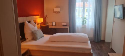 ein Schlafzimmer mit einem weißen Bett, einem Schreibtisch und einem Fenster in der Unterkunft Hotel Pflug in Dornhan
