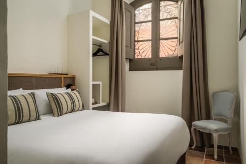a bedroom with a bed and a chair and a window at BYPILLOW Cluc Begur in Begur