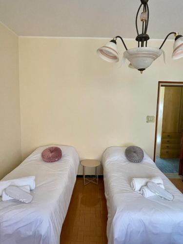 two beds in a room with a chandelier at appartamento Graziana in San Bonifacio