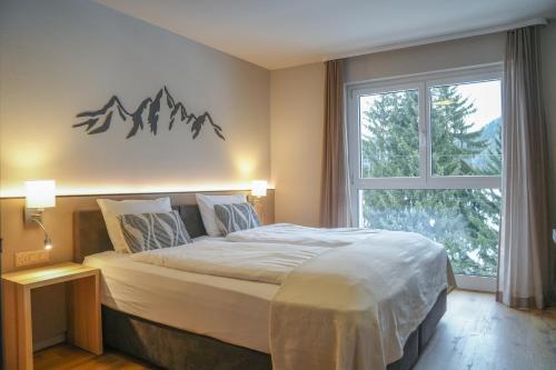 a bedroom with a bed and a window with a mountain sign on the wall at Studio 54 Davos in Davos