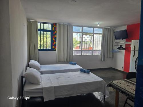 two beds in a room with two windows at Pousada do Luquinhas in Brasília