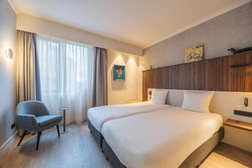 a hotel room with a large bed and a chair at Postillion Utrecht Bunnik in Bunnik