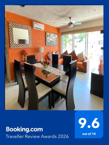 a dining room with a table and chairs and a couch at Hermoso departamento con alberca in Acapulco