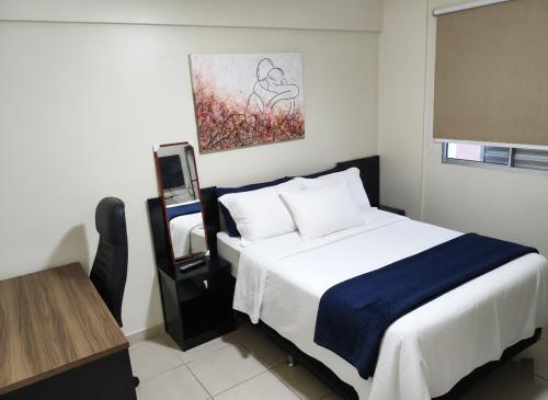 a bedroom with a bed and a table and a painting at Apto 2Q Centro Wifi Shopping Garage in Taubaté