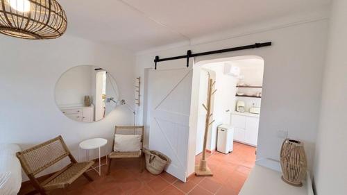 a white room with chairs and a table and a mirror at Casa Branca in Sesimbra