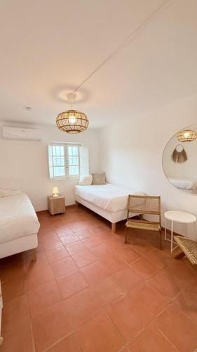 a bedroom with two beds and a table and a mirror at Casa Branca in Sesimbra