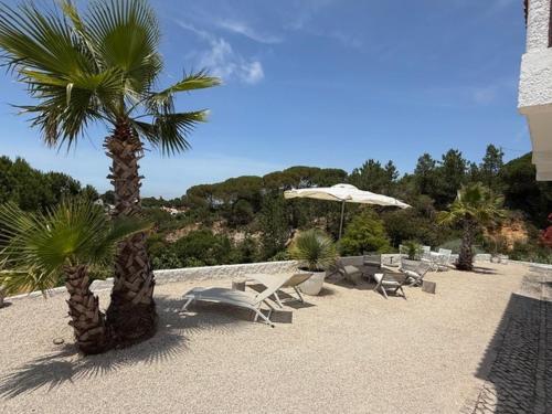 a beach with chairs and an umbrella and palm trees at Casa Branca in Sesimbra