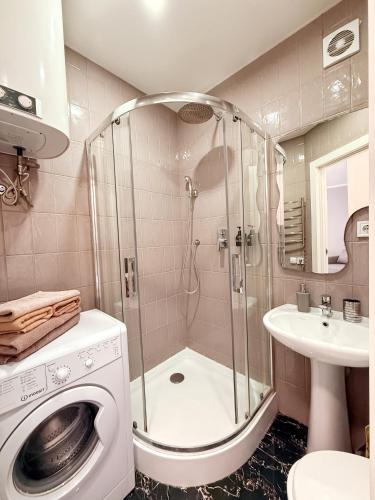 a bathroom with a shower and a washing machine at Kyiv Lesi 3 Studio Apartment in Kyiv