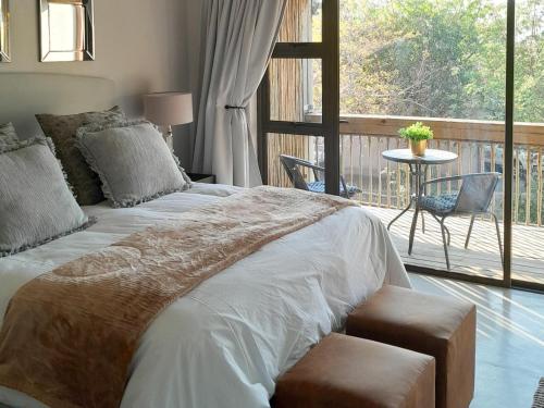 a bedroom with a large bed with a balcony at The Lofts in Hoedspruit
