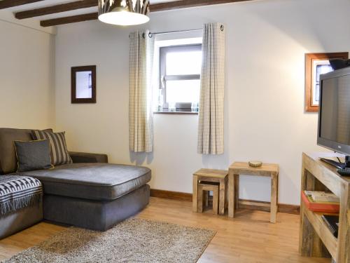 a living room with a couch and a tv at The Nook in Amroth
