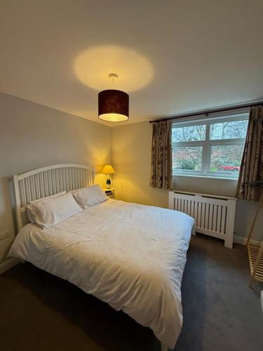 a bedroom with a white bed and a window at Unique Vicarage Town Cottage in Leominster