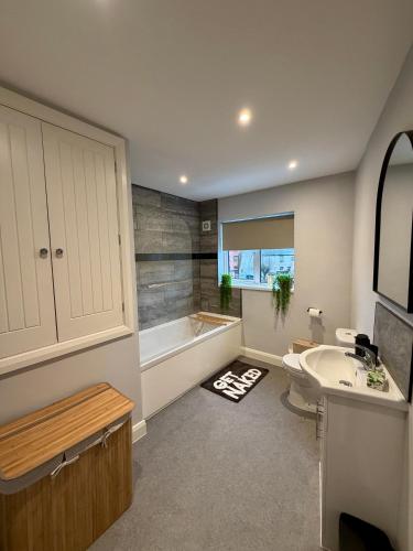 a bathroom with a tub and a toilet and a sink at Unique Vicarage Town Cottage in Leominster
