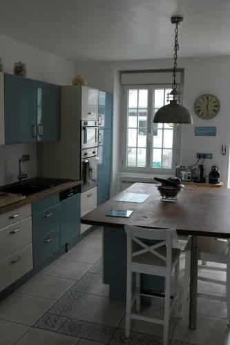 a kitchen with blue cabinets and a table in it at La Maison d'Adonis à la mer in Crozon