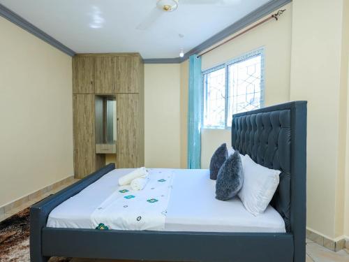 a bedroom with a bed with a black headboard and pillows at Heavenly homes apartment in Mombasa