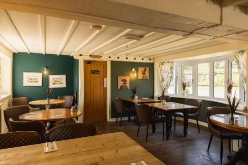 a restaurant with wooden tables and chairs and green walls at The Haughmond in Shrewsbury