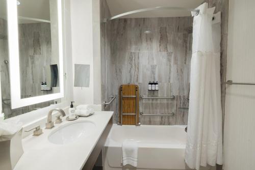a white bathroom with a sink and a shower at voco Hotel Napoleon Memphis by IHG in Memphis