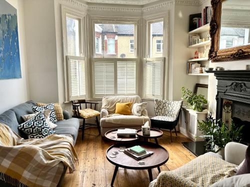 a living room with two couches and a table at Cosy Victorian house with free parking & fireplace in London