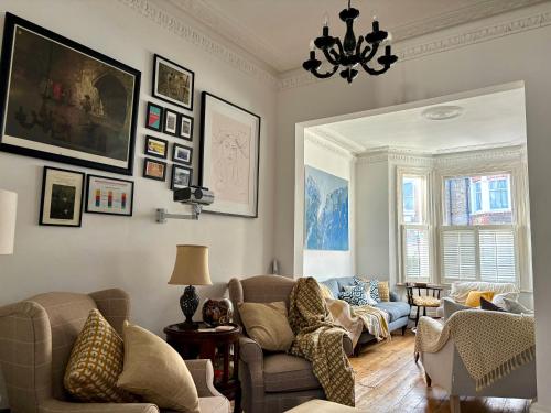 a living room with a couch and chairs and a chandelier at Cosy Victorian house with free parking & fireplace in London